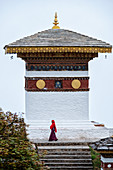Single nun walking past temple at Dochula Pass, Bhutan, Asia