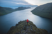 Frau steht auf Klakkur Berg und betrachtet den Fjord, Klaksvik, Färöer, Dänemark