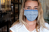Junge blonde Frau mit Gesichtsmaske steht in einem abfallfreien Naturkostladen