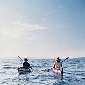 Middle aged man and woman sea kayaking on calm waters