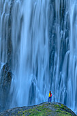 Woman while hiking looks at waterfall, Engstligenfall, Adelboden, Bernese Alps, Bern, Switzerland