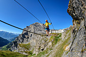 Frau am Erlebnisklettersteig Gemmi geht über Seilbrücke, Daubenhorn im Hintergrund, Gemmi, Berner Alpen, Wallis, Schweiz
