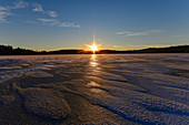 Sonnenaufgang über einem vereisten See bei Lycksele, Västerbottens Län, Schweden