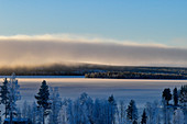 Wolkenwand und Blick auf einen See und verschneiten Wald bei Dorotea, Lappland, Schweden