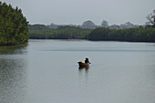 Gambia; Western Region; Boot auf dem Bintang Bolong; drei Jungen sitzen in dem Boot; fahren Richtung Hafen