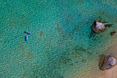 Zwei Frauen, die auf Luftmatratzen auf klarem, blauem Wasser schwimmen. Luftaufnahme, Britische Jungferninseln.