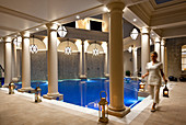 Abendaufnahme eines Spa-Therapeuten, der Lampen in einem Interior-Poolraum trägt. Bath, Vereinigtes Königreich