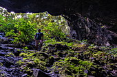 Man stands at the entrance to the Vaipori Cave, Tahiti Iti, Tahiti, Windward Islands, French Polynesia, South Pacific