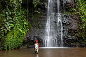 Schöne junge Tahitianerin vor Wasserfall in "The Water Gardens of Vaipahi", Teva I Uta, Tahiti, Windward Islands, Französisch-Polynesien, Südpazifik