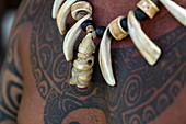 Detail einer Kette aus geschnitzten Walknochen an einem Mann mit Tätowierungen am Te Tumu-Kulturzentrum, Tekoapa, Ua Huka, Marquesas-Inseln, Französisch-Polynesien, Südpazifik