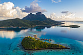 Luftaufnahme des Sofitel Bora Bora Private Island Resort mit Überwasserbungalows in der Lagune von Bora Bora mit Mount Otemanu bei Sonnenaufgang, Vaitape, Bora Bora, Leeward Islands, Französisch-Polynesien, Südpazifik