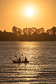 Silhouette von jungem Paar während Kajak Ausflug von Flusskreuzfahrtschiff auf dem Mekong bei Sonnenuntergang, nahe Preah Prosop, Fluss Mekong, Kandal, Kambodscha, Asien