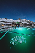 Mann, der auf gefrorenem See Sils läuft, beleuchtet durch Stirnlampe bei Nacht, Engadin, Kanton Graubunden, Schweiz, Europa