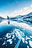 Man playing ice hockey on frozen Lake Sils covered of bubbles, Engadine, canton of Graubunden, Switzerland, Europe