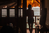 Rear view, a woman in a doorway looking out over sea.