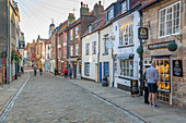 Ansicht der Geschäfte auf der traditionellen Kopfsteinpflasterstraße im historischen Stadtzentrum, Whitby, Yorkshire, England, Vereinigtes Königreich, Europa