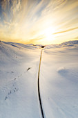 Luftaufnahme des brennenden Himmels im Morgengrauen über der malerischen Straße, die die schneebedeckten Berge, Sennalandet, Alta, Troms og Finnmark, Arktis, Norwegen, Skandinavien, Europa kreuzt