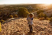 young boy in Galisteo Basin looking through binoculars at sunset