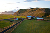 Church and small group of houses with car on road near Vik