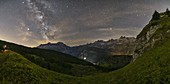 A panoramic view of Alpe Devero during night with Milky Way and a photographer, Verbano Cusio Ossola, Piedmont, Italy, Southern Europe