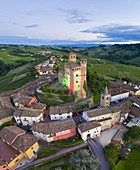 Aerial view of the medieval town of Serralunga d'Alba and its castle at the blue hour light painted with the colors of the italian flag. Serralunga d'Alba, Langhe, Piedmont, Italy, Europe.