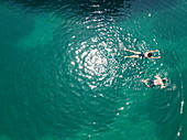 Aerial view of couple swimming in the clear water of a pristine bay, near Rab, Primorje-Gorski Kotar, Croatia, Europe