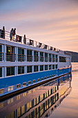 Paar auf Sonnendeck von Flusskreuzfahrtschiff  während einer Kreuzfahrt auf dem Rhein bei Sonnenuntergang, Rüdesheim am Rhein, Hessen, Deutschland, Europa