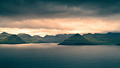 Sonnenuntergang über den Bergen der Küste von Eysteroy, Färöer Inseln\n