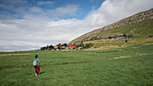 Frau wandert zu Dorf Kirkjubøur auf Streymoy, Färöer Inseln\n