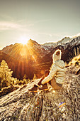Frau sitzt auf Felsen in Maloja und genießt den Sonnenuntergang, Engadin, Graubünden, Schweiz, Europa