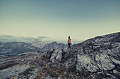 Frau mit Kamera steht auf einem Berg beim Lünersee, Vorarlberg, Österreich, Europa
