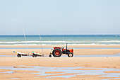 Traktor am Strand mit Anhänger für Kitebuggys- Omaha Beach, Calvados, Frankreich.