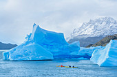 Kajakfahrer paddeln unter Eisbergen, Nationalpark Torres del Paine, Patagonien, Chile, Südamerika