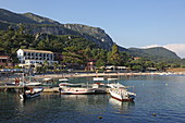 Der Strand von Agios Spiridon im Ort Paleokastritsa ist zwischen zwei Halbinseln gelegen. Von der Pier starten Ausflugsboote, Insel Korfu, Ionische Inseln, Griechenland