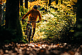 Mountainbiker fährt durch herbstlichen Wald