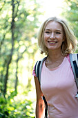 Porträt der lächelnden reifen Frau, die im Wald steht