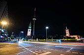 Low angle view of church and Fernsehturm Berlin with traffic on street in foreground at night