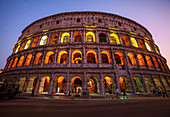 Low angle view of tourists walking on street outside Colosseum at dusk,Rome