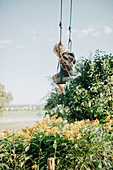Little boy swings in the garden, yellow flowers, swings, joy, Allgäu, Bavaria