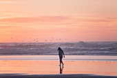 Frau spaziert im Sonnenuntergang am Strand, Portugal