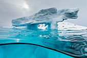 Above and below view of an arch formed in an iceberg at Cuverville Island, Ererra Channel, Antarctica, Polar Regions