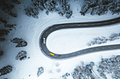 Aerial view of cars driving on bends of snowy mountain road in winter, Switzerland, Europe
