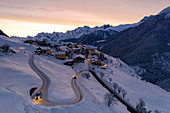 Cars driving on hairpin bends of snowy road at dawn, Guarda, Lower Engadine, Graubunden Canton, Switzerland,  Europe