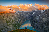 Mann, der auf Felsen steht, die Wolken am Sonnenuntergang über See Limmernsee, Luftbild, Kanton Glarus, Schweiz, Europa betrachten
