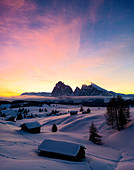 Berghütten bedeckt mit Schnee im Morgengrauen mit Sassopiatto und Sassolungo im Hintergrund, Seiser Alm, Dolomiten, Südtirol, Italien, Europa