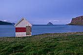 Blaue Stunde in einem kleinen Holzhaus am Meer auf Suduroy, Färöer, Dänemark, Europa