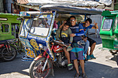 Drei glückliche Männer warten vor einer dreirädrigen Rikscha in Romblon Town, Barangay I, Romblon, Romblon, Philippinen, Asien
