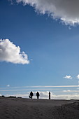 Zwei Menschen laufen entlang Dünen mit dem Leuchtturm von Ameland dahinter, nahe Hollum, Ameland, Westfriesische Inseln, Friesland, Niederlande, Europa