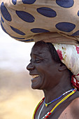 Angola; westlicher Teil der Provinz Cunene; Frau mit Gepäck auf dem Kopf; an der Straße unterwegs