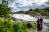 Familie bestaunt Wasserfall, Der Fluss Vefsna mit dem Wasserfall Laksfossen, Norwegen